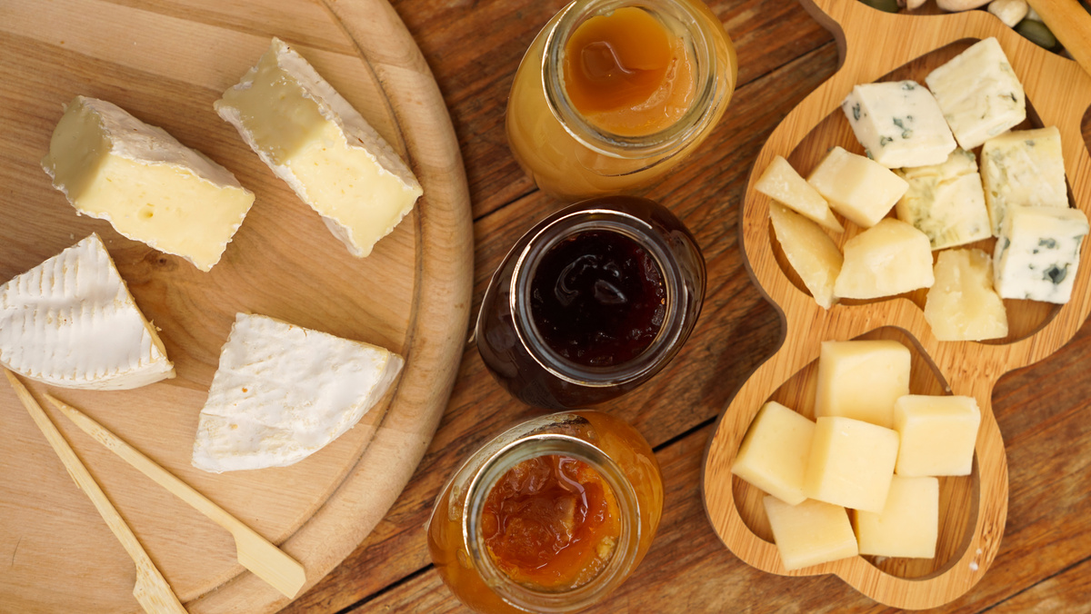 Jars of Homemade Jams and a Variety of Cheeses on a Wooden Table. Cheese Plate